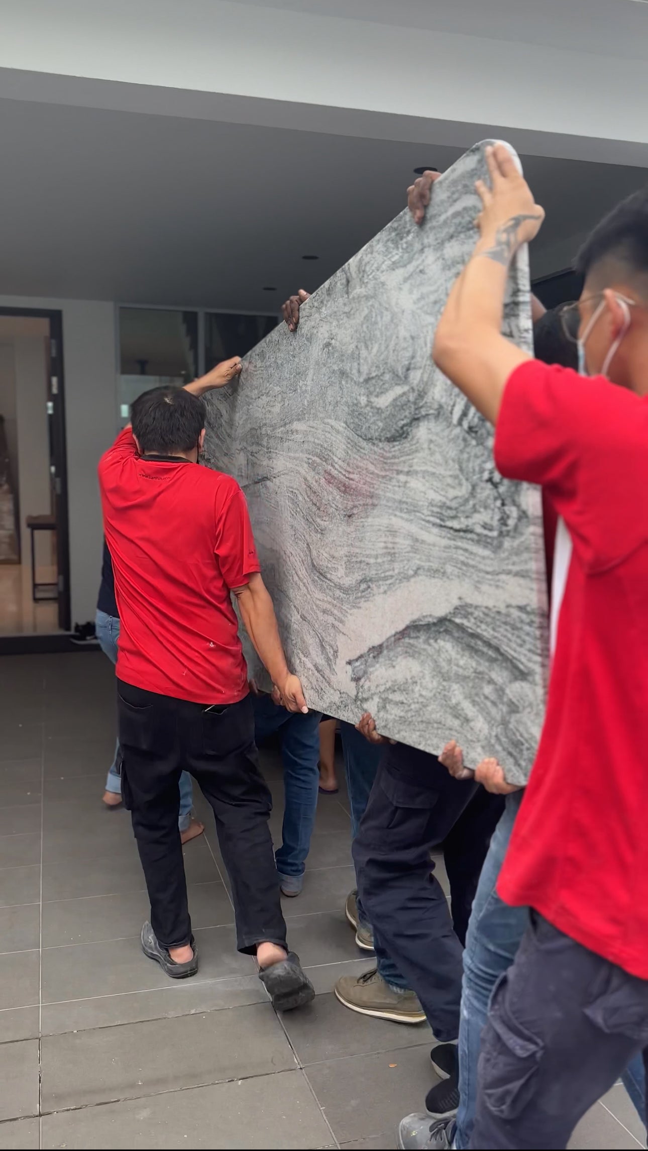 6 men moving solid granite slab into home for dining table